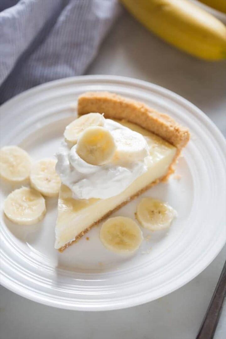 Banana Cream Pie Slice On A White Plate with Fresh Banana Slices On Top of Whipped